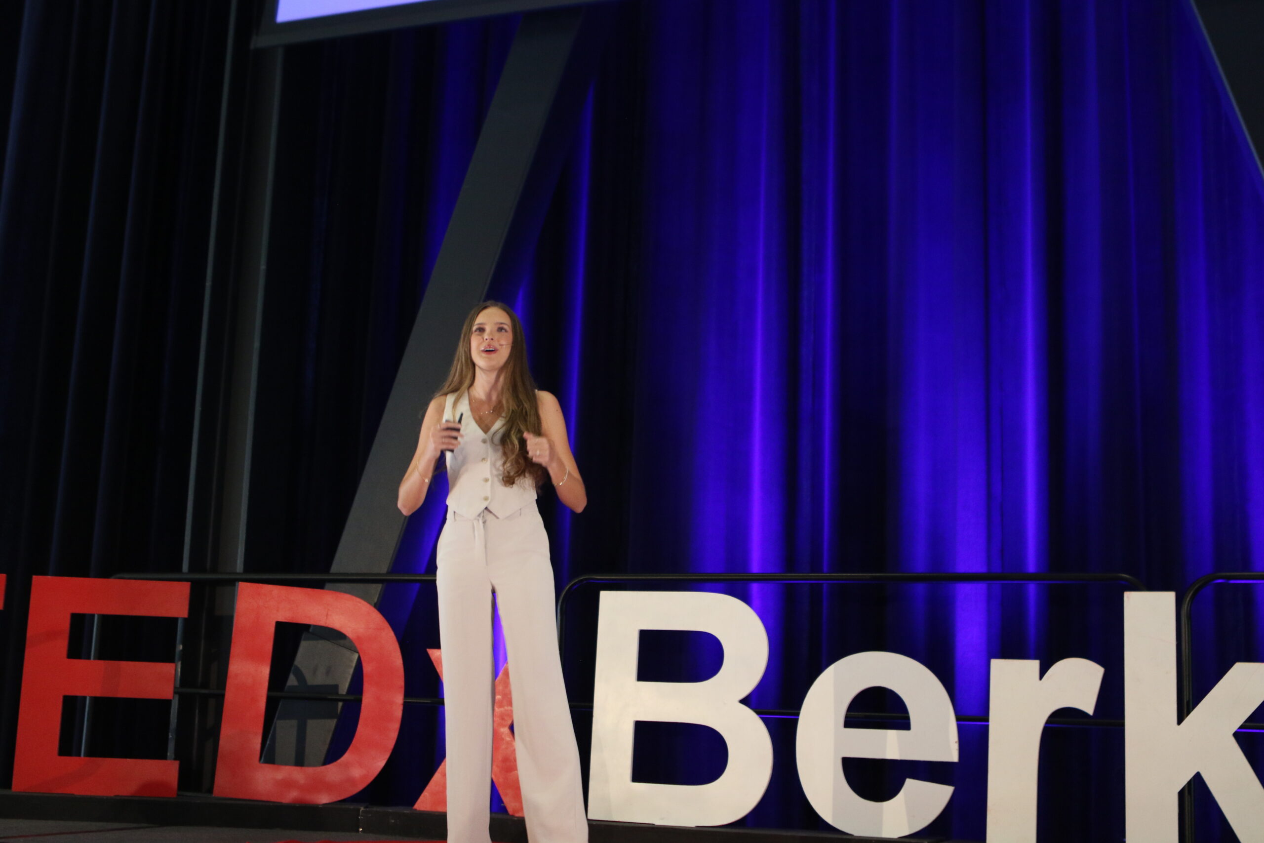 Jasmine Ornish speaking in front of the large TEDxBerkeley letters on stage