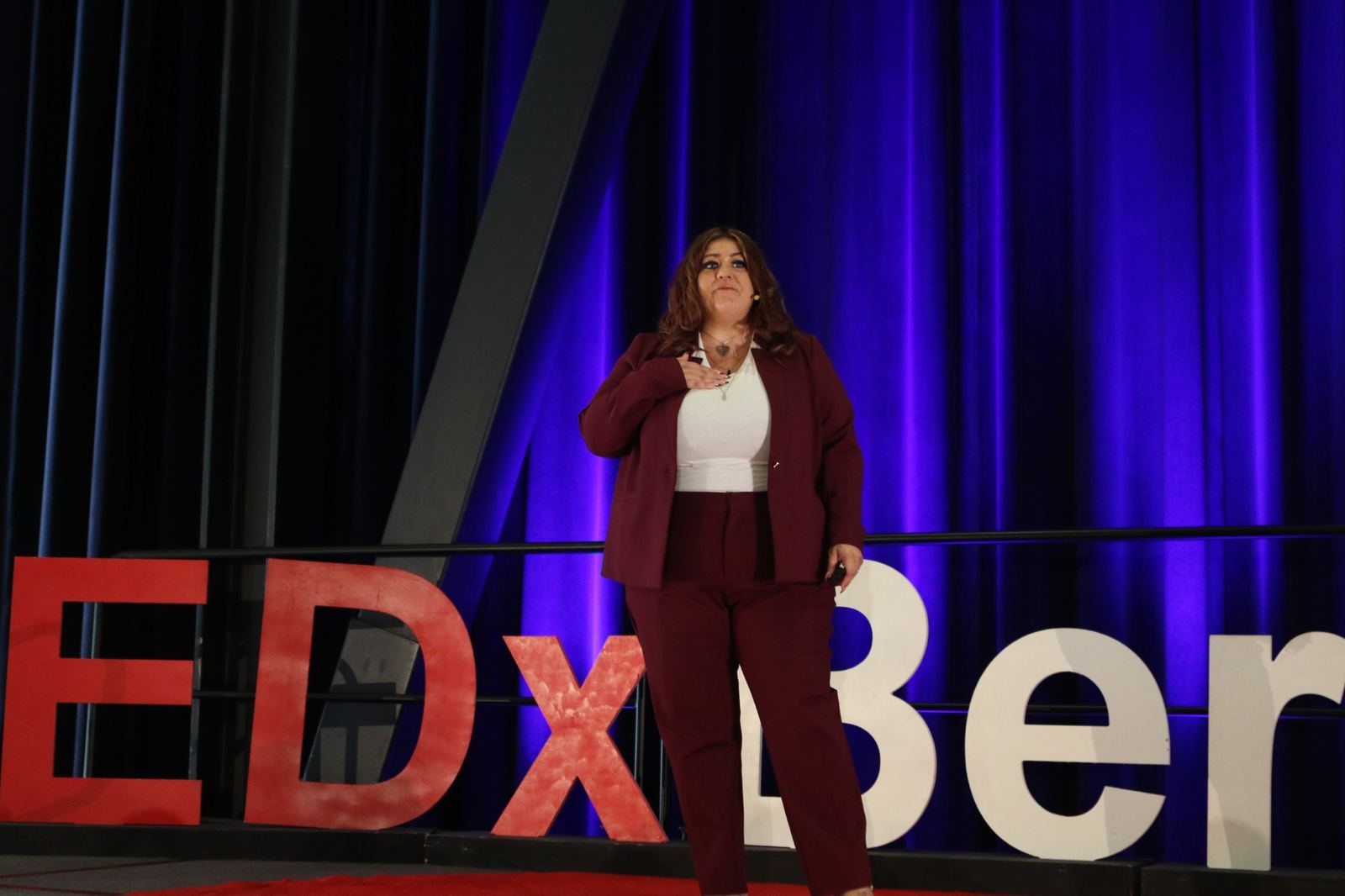 Alicia Baker with a hand on the heart while speaking at TEDxBerkeley 2026